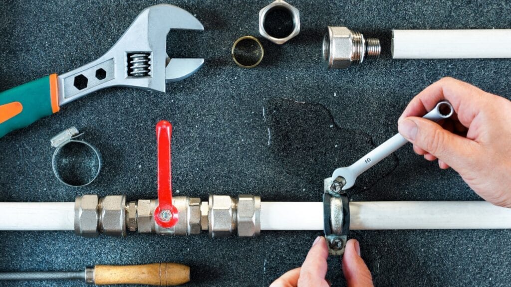Plumber repairing a pipe valve with an adjustable wrench in Hialeah