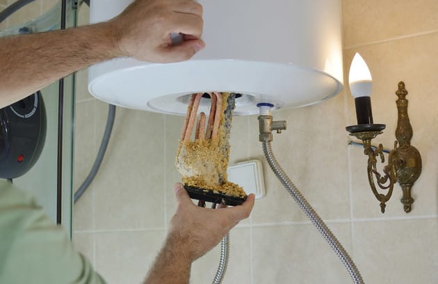 Technician removing mineral buildup from a water heater in Hialeah
