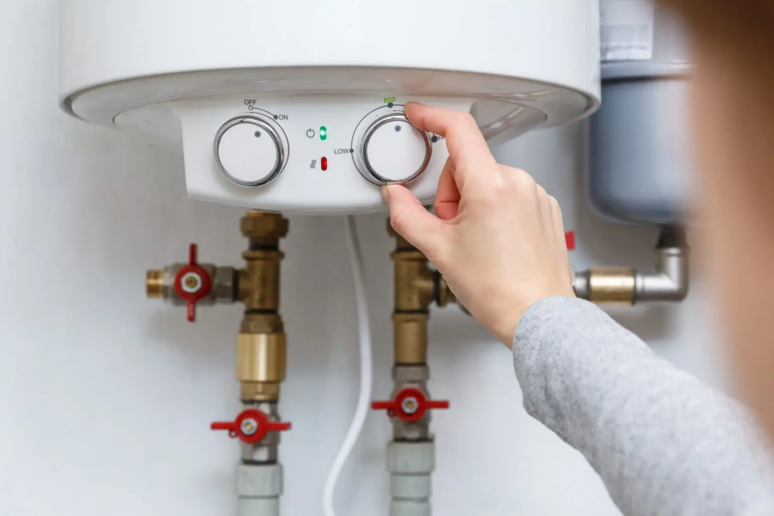 Homeowner adjusting the temperature controls on a water heater in Hialeah